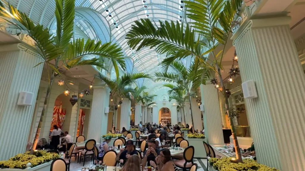 Seating area inside the Buffet at Wynn with glass ceilings and palm trees overhead. 