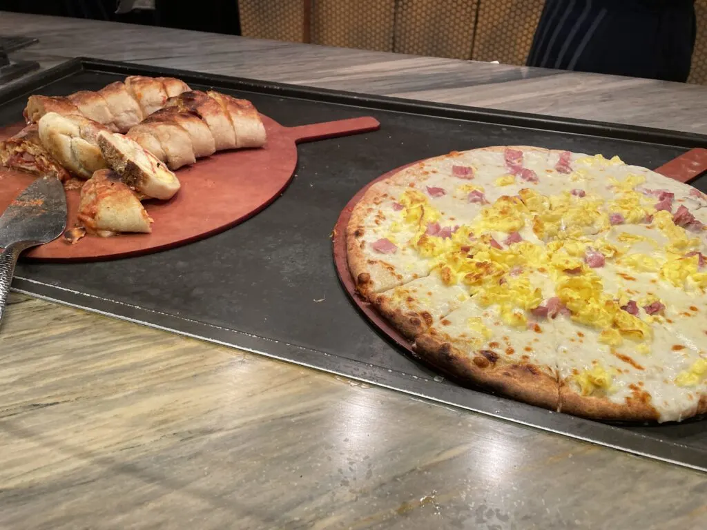 A breakfast pizza topped with scrambled eggs and breakfast stromboli