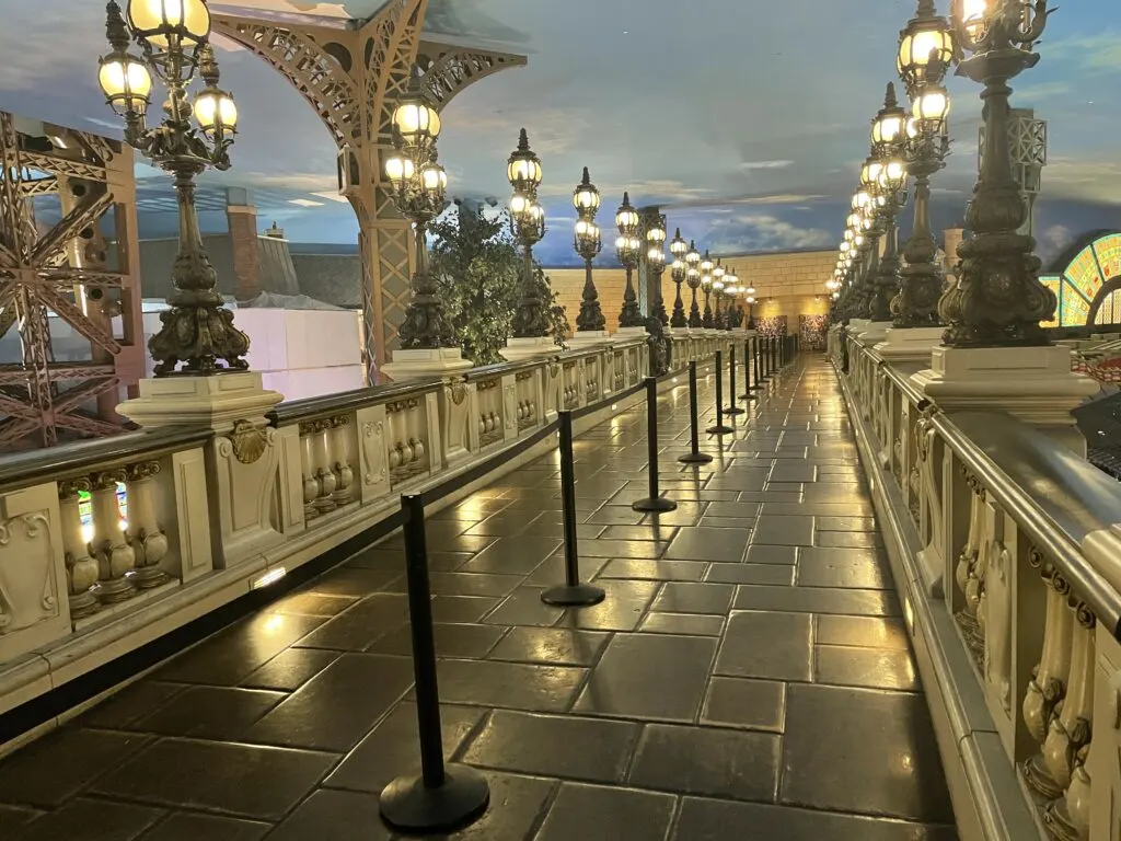 A cobblestone bridge devoid of people lined on either side by Parisian streetlights. 