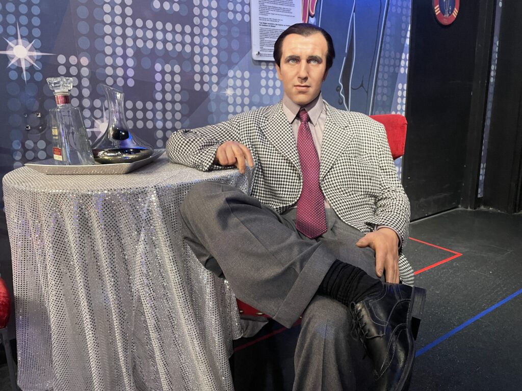 A wax figure of Bugsy Siegel sits at a table
