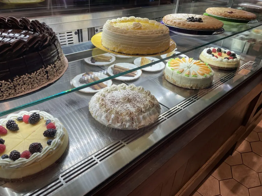 A number of cakes and pies on display in a fridge case