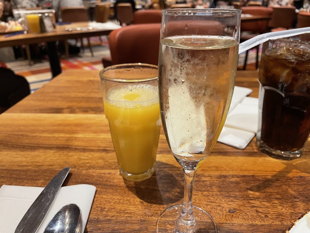 A glass of champagne sits next to a glass of orange juice