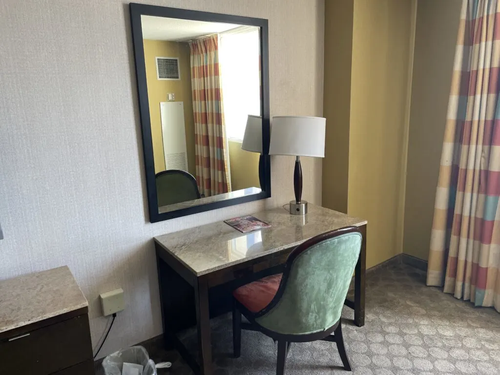 Workdesk with a lamp, chair, and a mirror hanging above. 