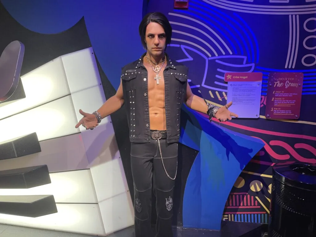 Criss Angel poses in all black holding his hands out to his side with palms facing up.