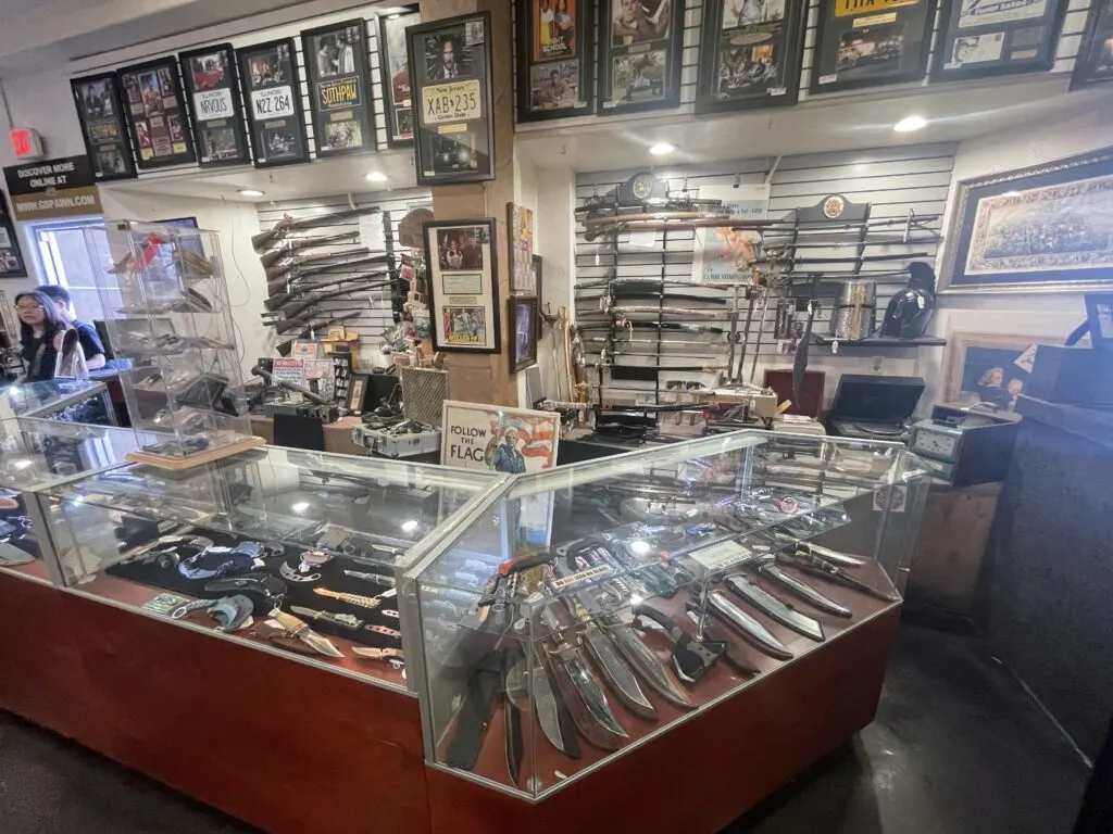 Knives and firearms on display on the wall and in cases