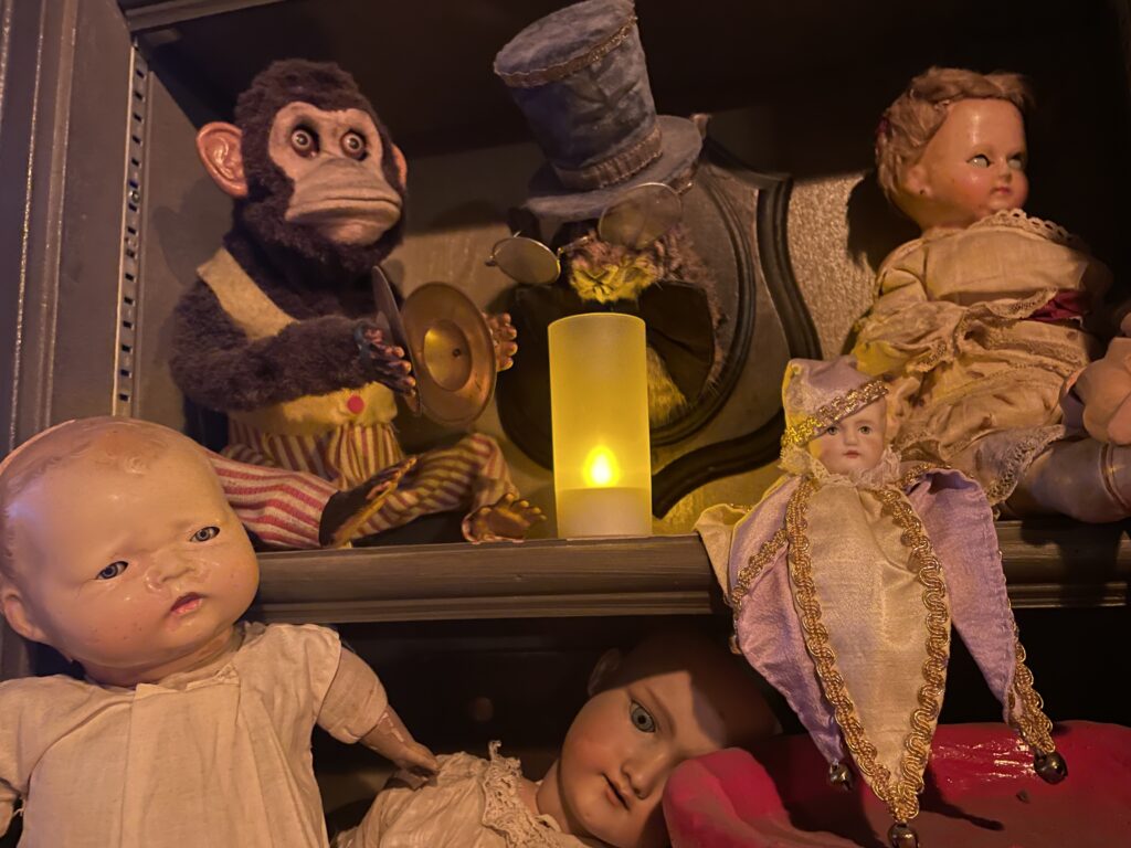Dolls sitting on shelves surrounding a fake candle