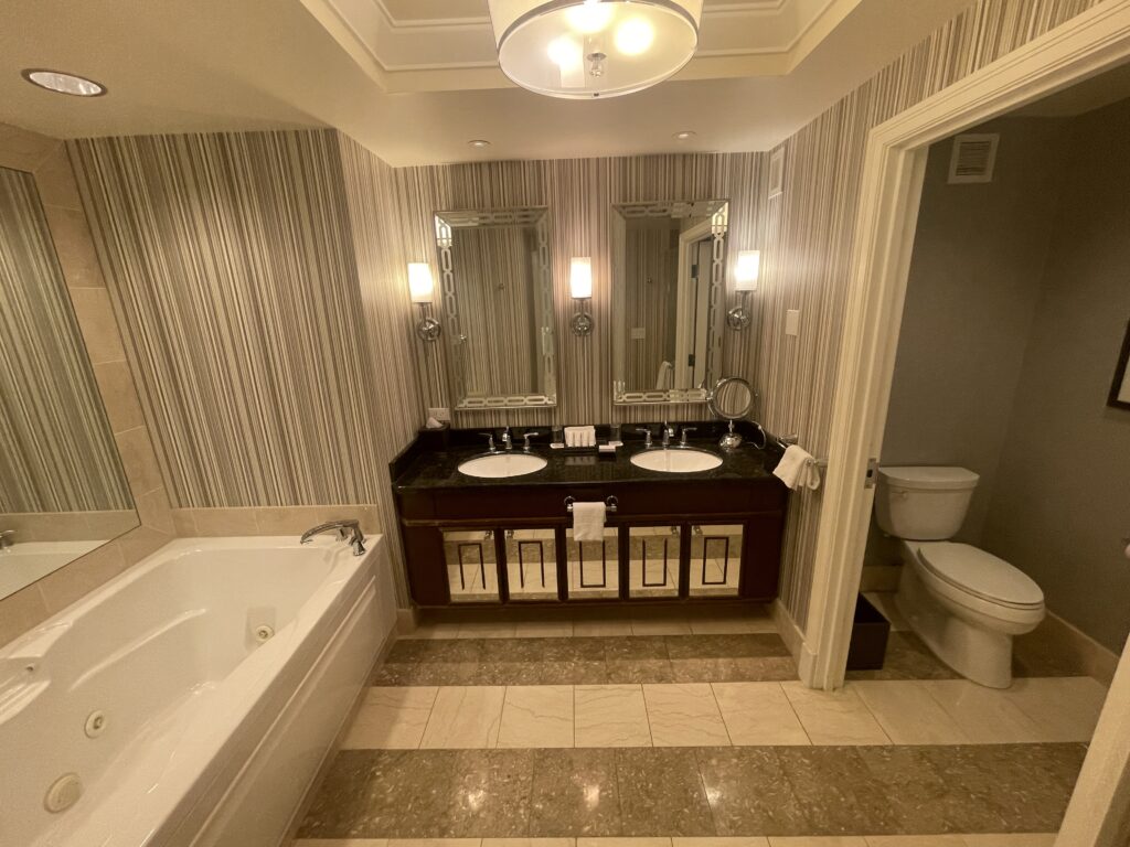 A dual sink vanity with two mirrors hanging above it. To the left is a bathtub, and a toilet to the right.