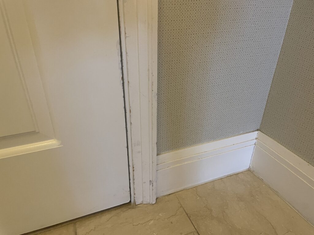 Scuffs on the white trim on the right side of the hotel room door.