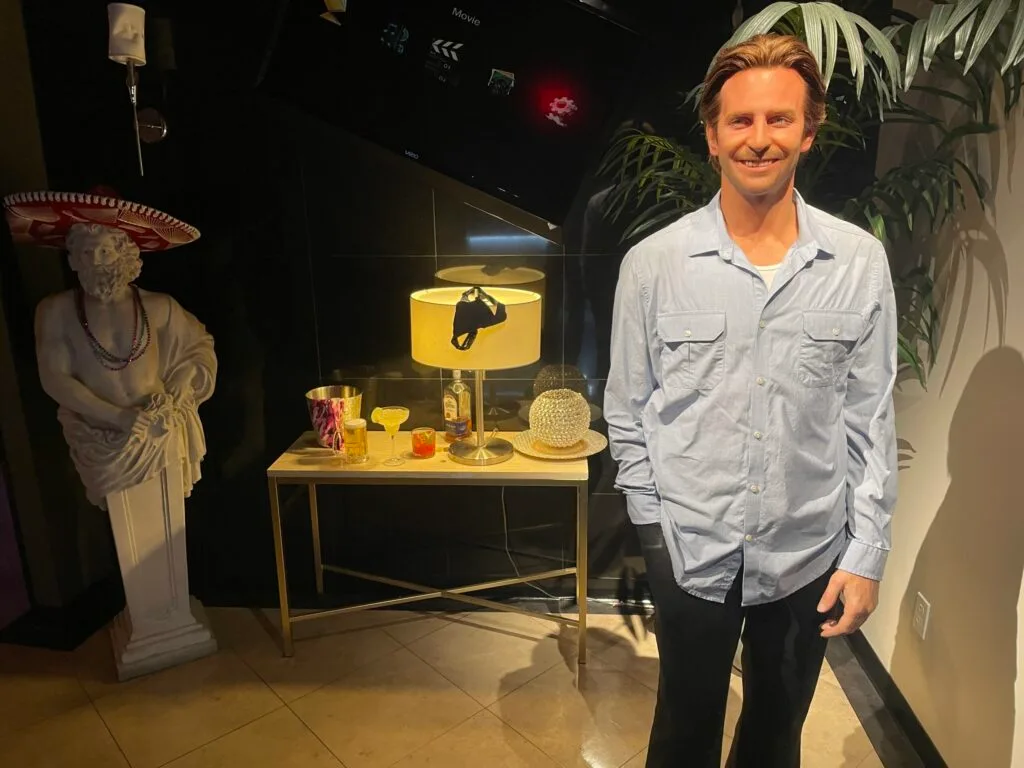 Phil from the Hangover poses in a scene depicting a trashed hotel room.