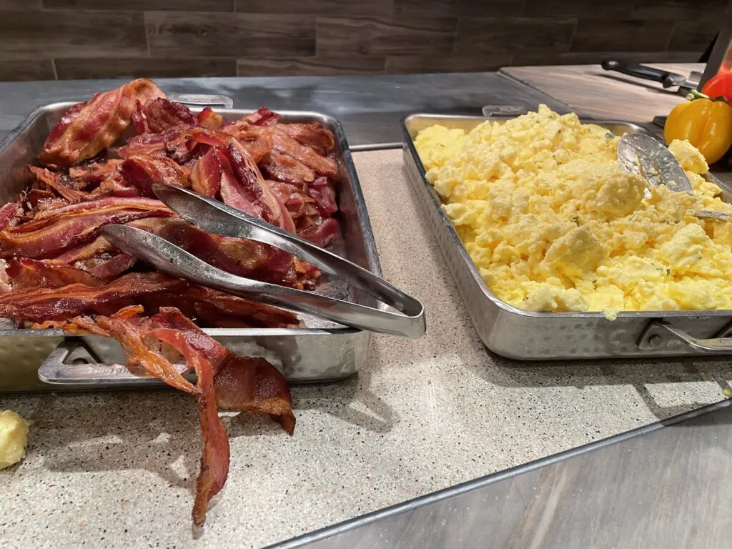 A pile of bacon next to a pile of scrambled eggs