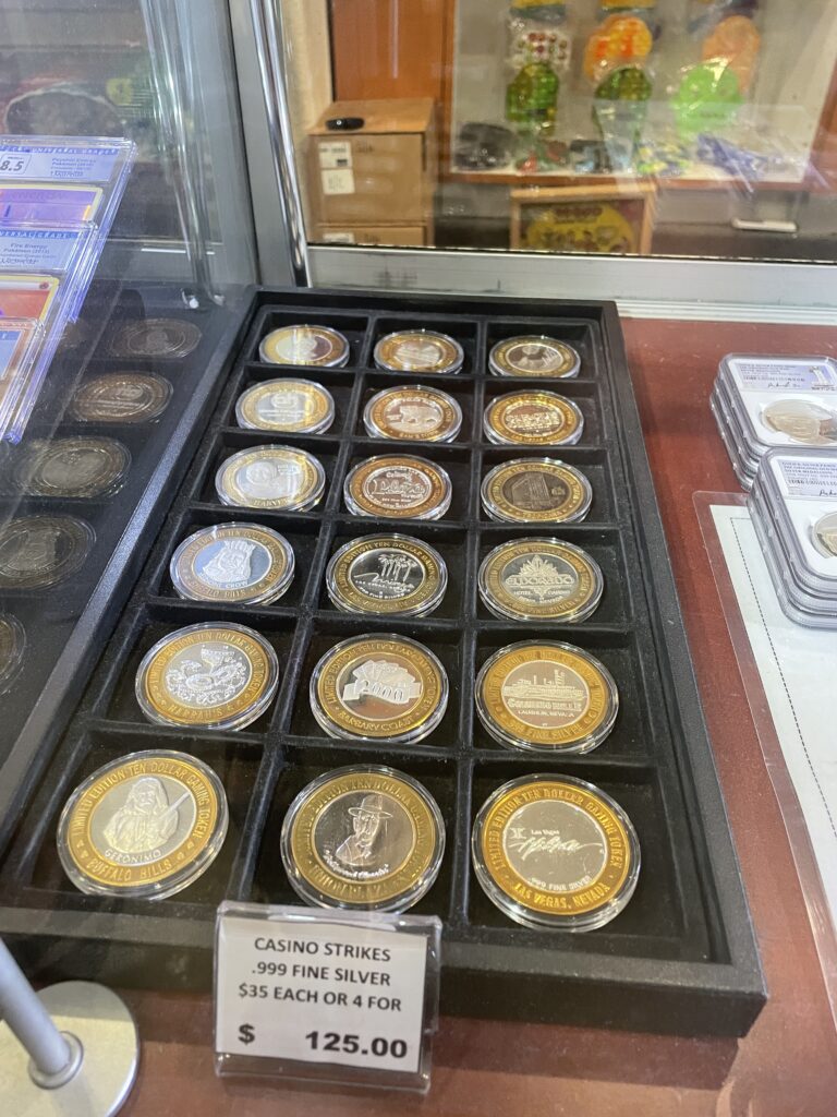 Silver Strike slot tokens for sale under a glass counter
