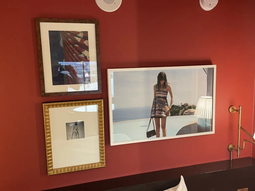 3 pictures of different sizes hanging above the bed on the red accent wall. 