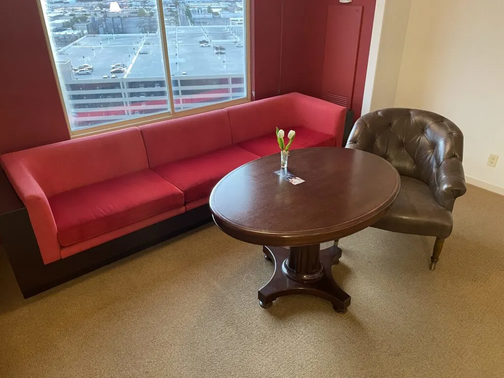 A brown table, brown leather chair, and red couch.