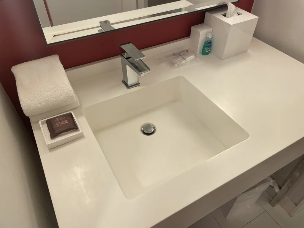 Bathroom sink with toiletries like soap, mouthwash, toothbrush, and a shave kit.