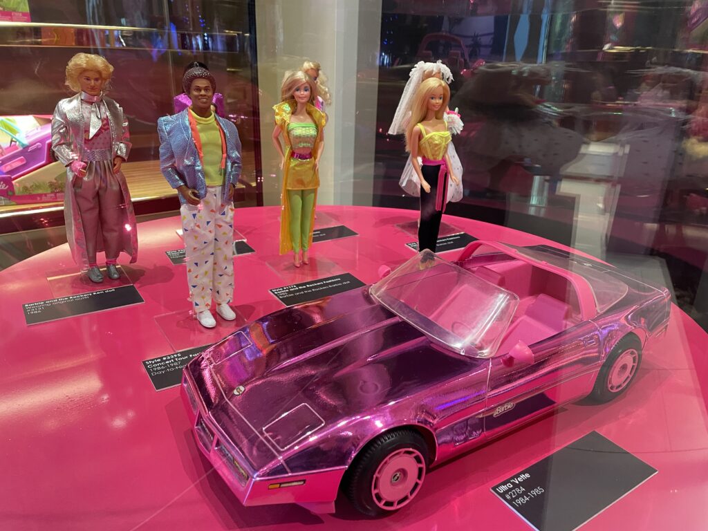 1980's fashion on dipslay, with a pink shiny Barbie Corvette also displayed. 
