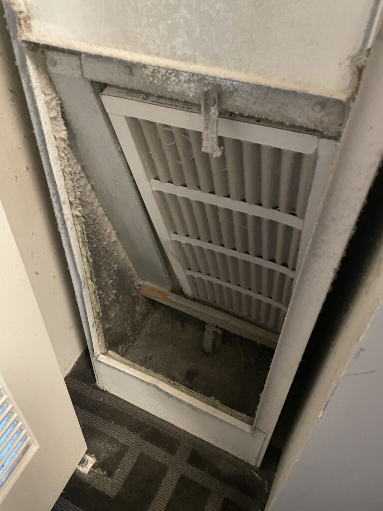 A very dusty air filter covering the intake of the room's HVAC system.