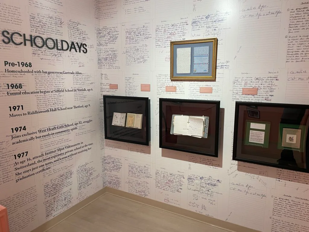 A room of the exhibit with Diana's schoolwork haning everywhere. Examples of her schoolwork is even used as wallpaper.