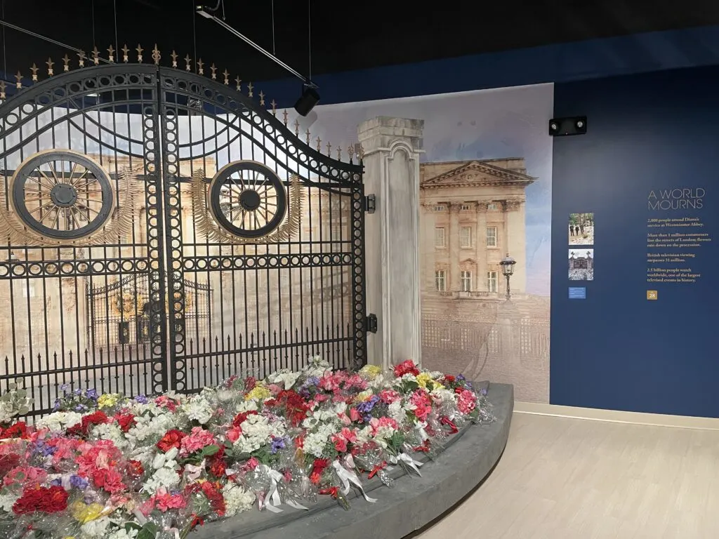 A replica memorial depicting a pile of flowers at a gate. 