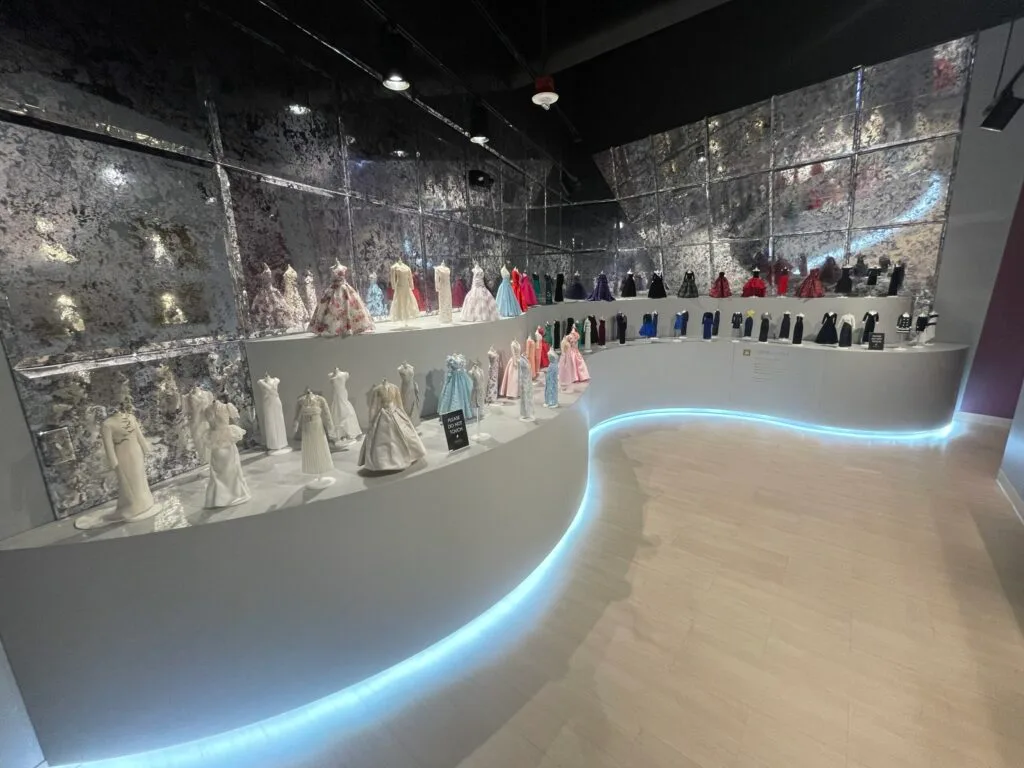 A room with a ton of doll-sized replica dresses on display.