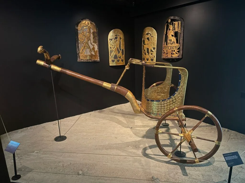 A golden charriot with 2 large wheels.