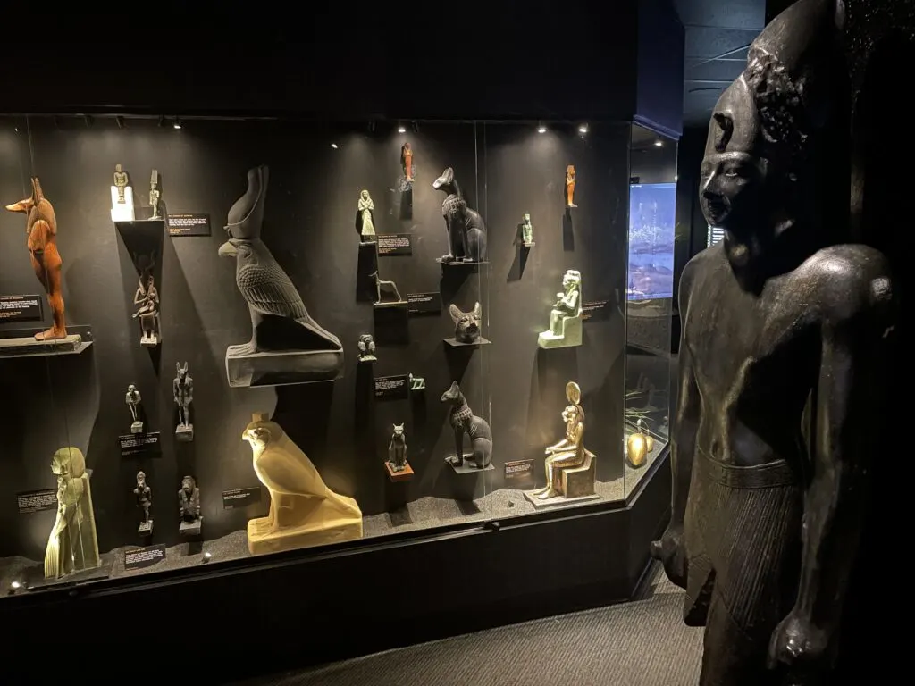 a number of statues are housed in a glass case. 