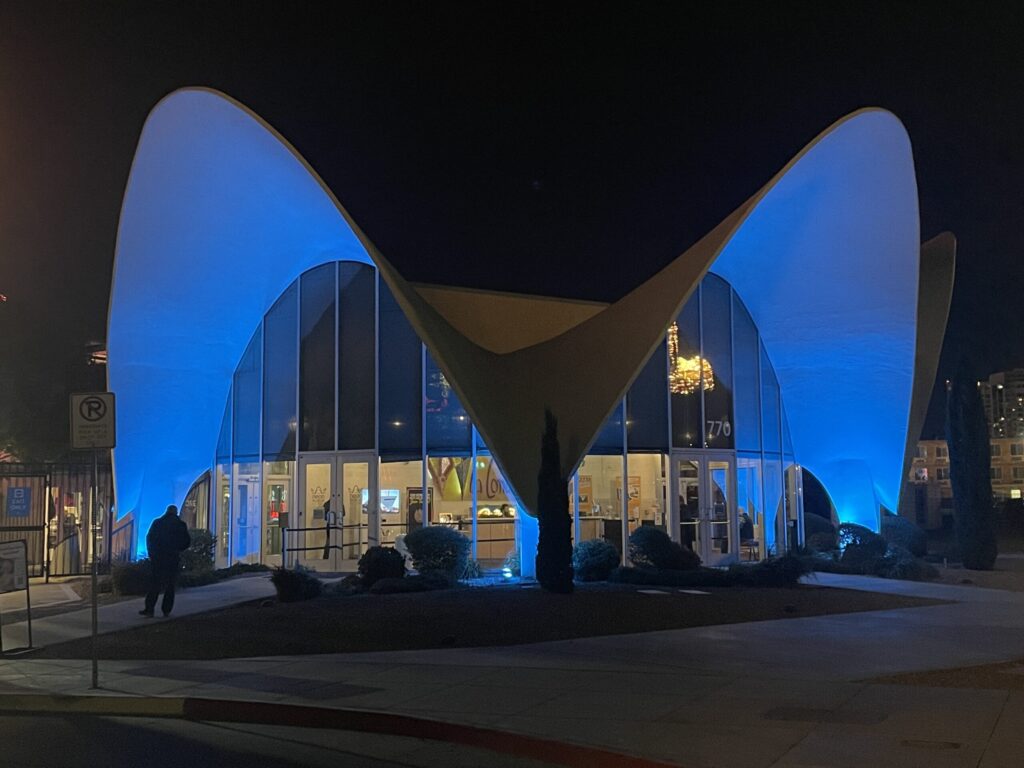The La Concha motel lobby illuminated in blue at night.