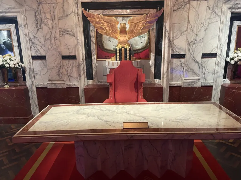 President Snow's desk and chair photographed head on. Behind the chair is a golden statue.