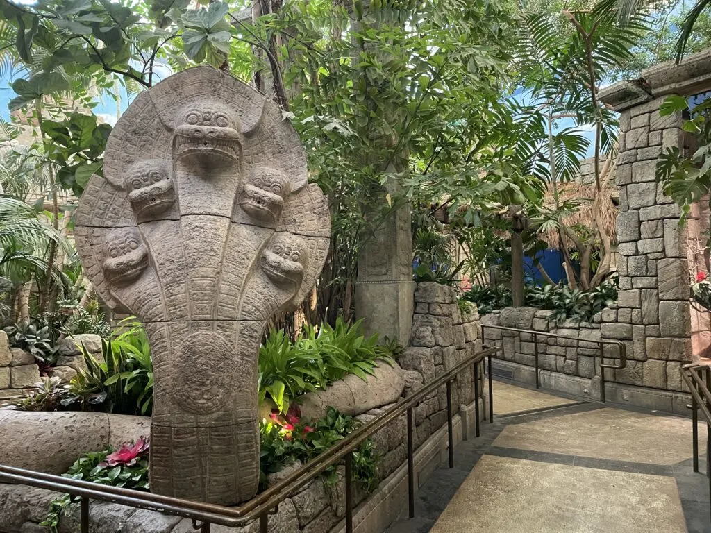 A stone sculpture emerges from the green plant life along the path in the zoo portion of Shark Reef. 