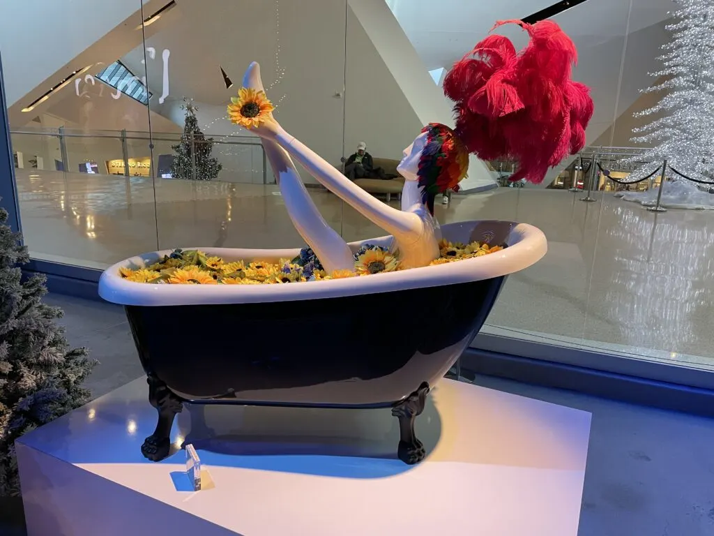 A mannequin sitting in a bathtub full of sunflowers.