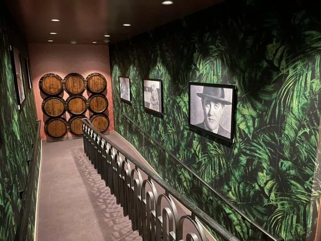 A pathway leading to the speakeasy that is lined with pictures of gangsters, and even  a stack of fake wooden barrels. 