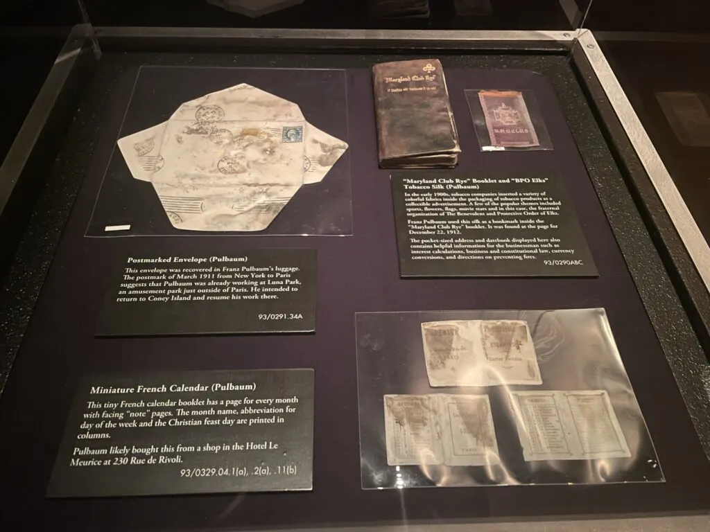 Belongings of Franz Pulbaum in a display case that includes paper documents, an envelope and a small booklet.
