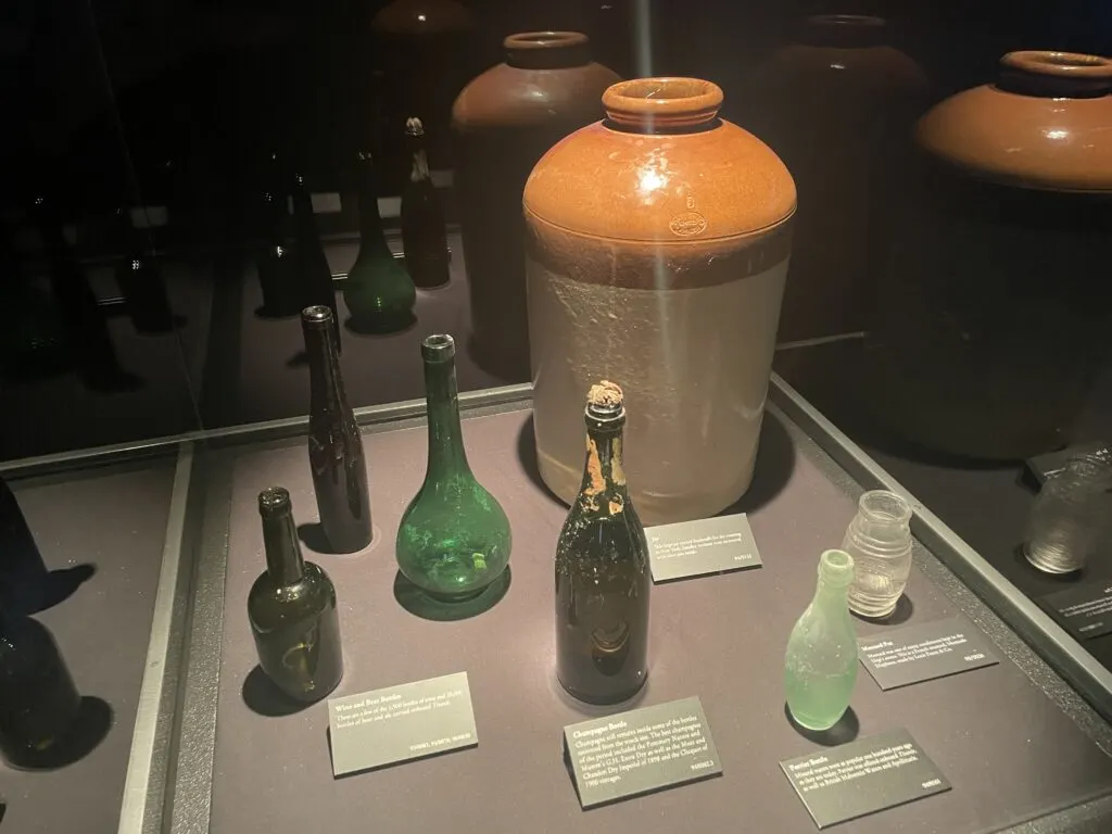Various bottles that once held beverages in a display case. 
