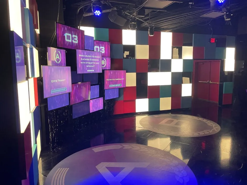 A room with a TV screen displaying trivia questions. On the floor are two giant circles labled A and B, that you stand in to answer the question on the screen. 