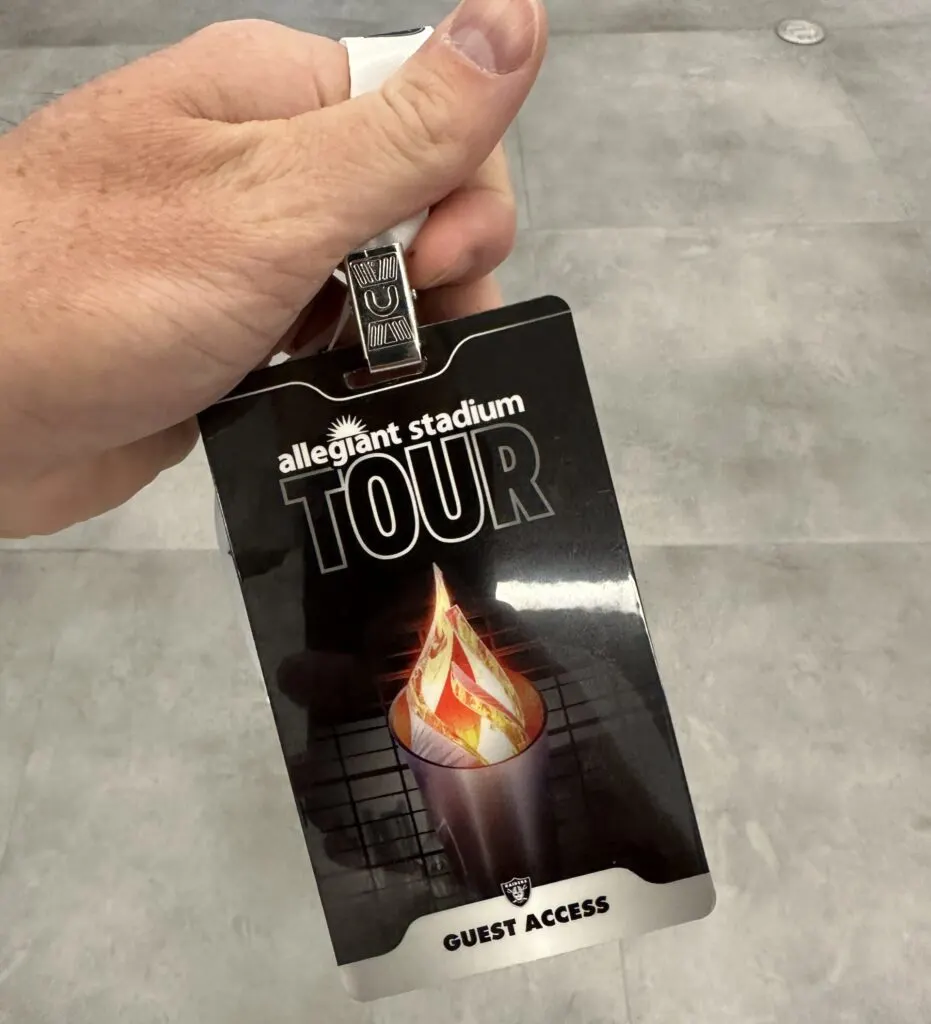 A hand holding a pass that says "Allegiant Stadium TOUR".
