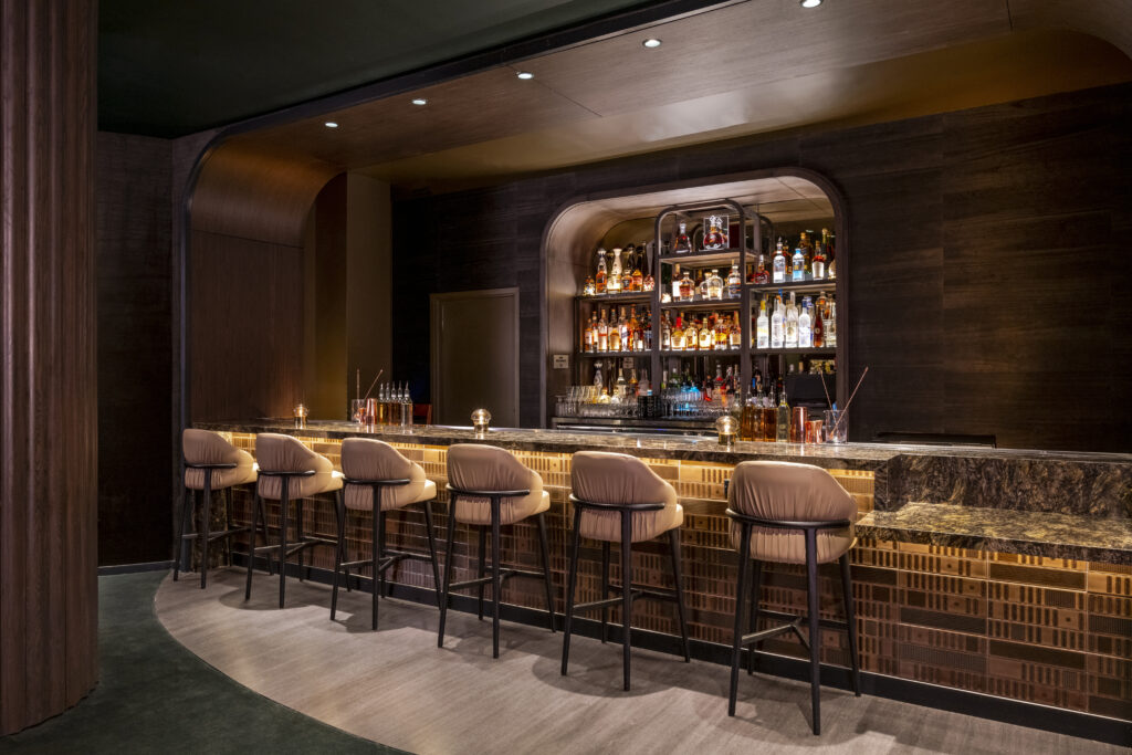 The bar at Easy's with 6 stools lined up, and illuminated spirit bottles behind the bar.