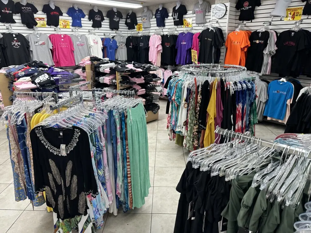 Women's shirts on numerous racks, and hung on the wall in the background. 