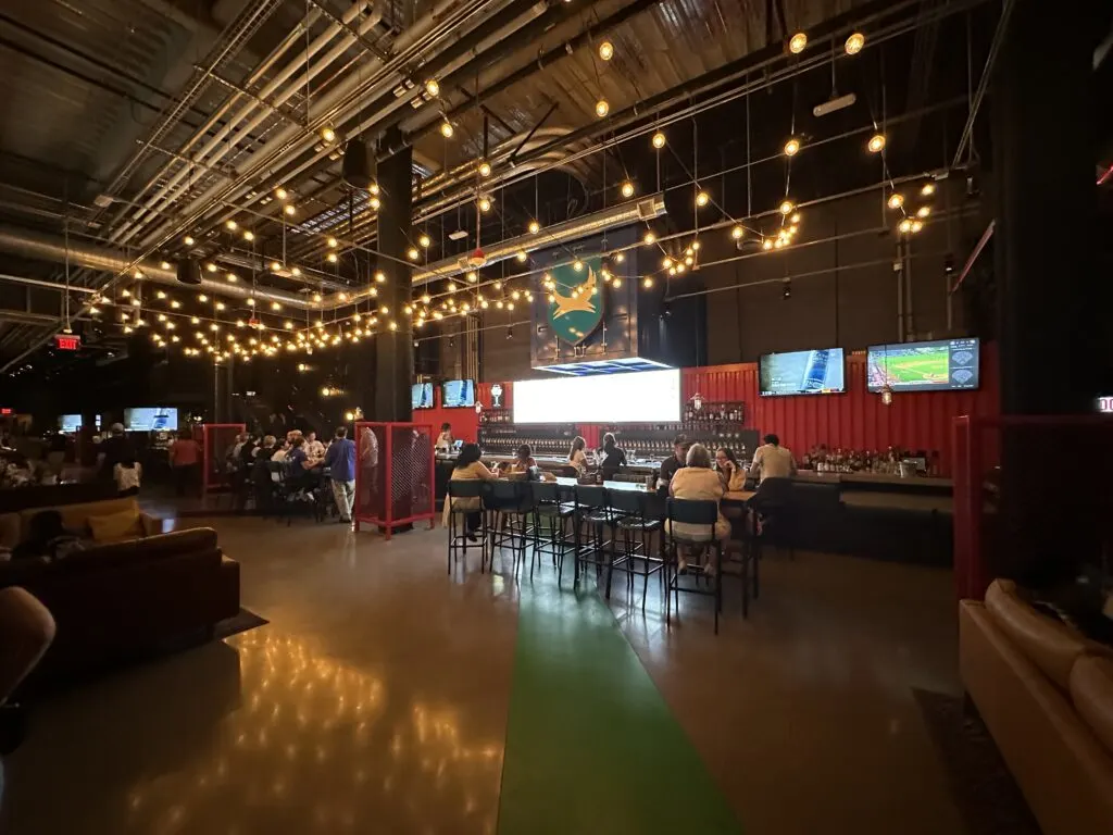 A bar downstairs at Brewdog with a red background and an illuminated sign behind it. 