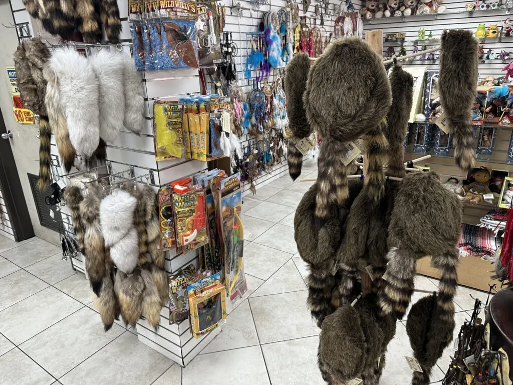 Fur raccoon hats in the style of Davey Crockett hange from a rack. 