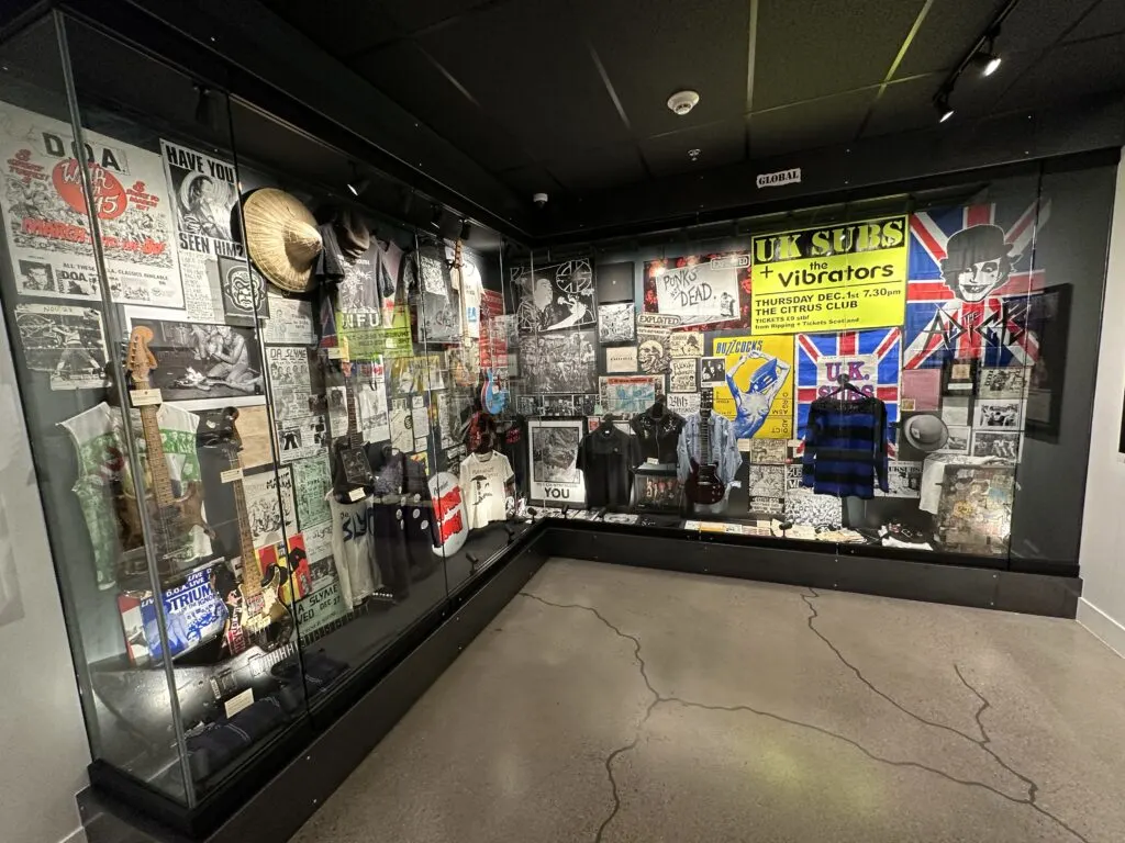 ARtifacts behind glass that include guitars, posters, and clothing that are from punk bands from around the globe.