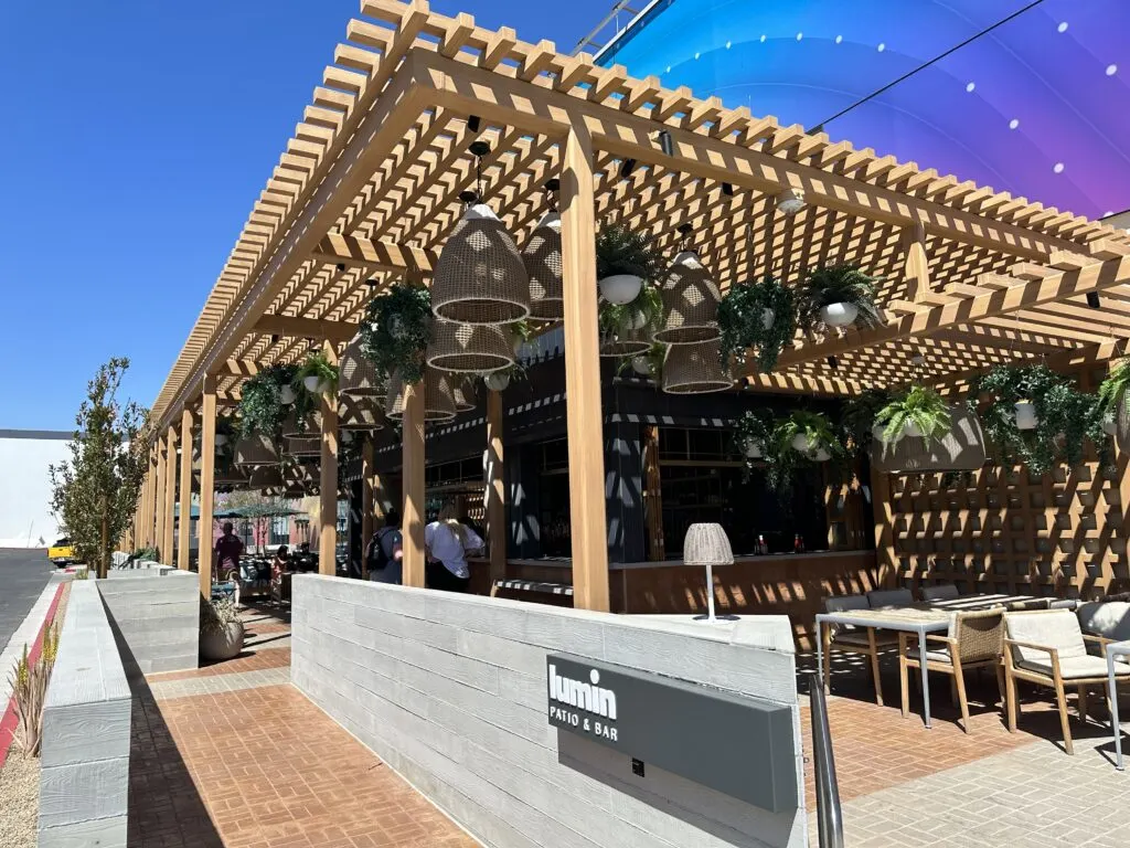 Ourdoor patio bar at Illuminarium with a wooden trellis built over it for shade. 