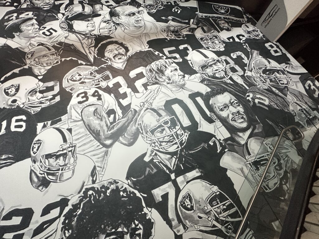 A black and white mural depicting many great Raiders from over the decades. 