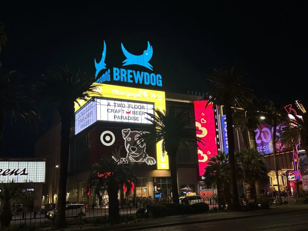 The Showcase Mall illuminated at night. Target and Ross are on the street level, while BrewDog's sign is illuminated atop the building.