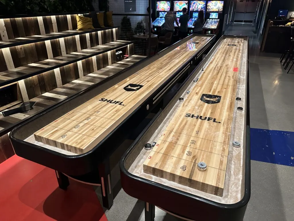 2 long wooden shuffleboard tables sit side by side at Brewdog. 