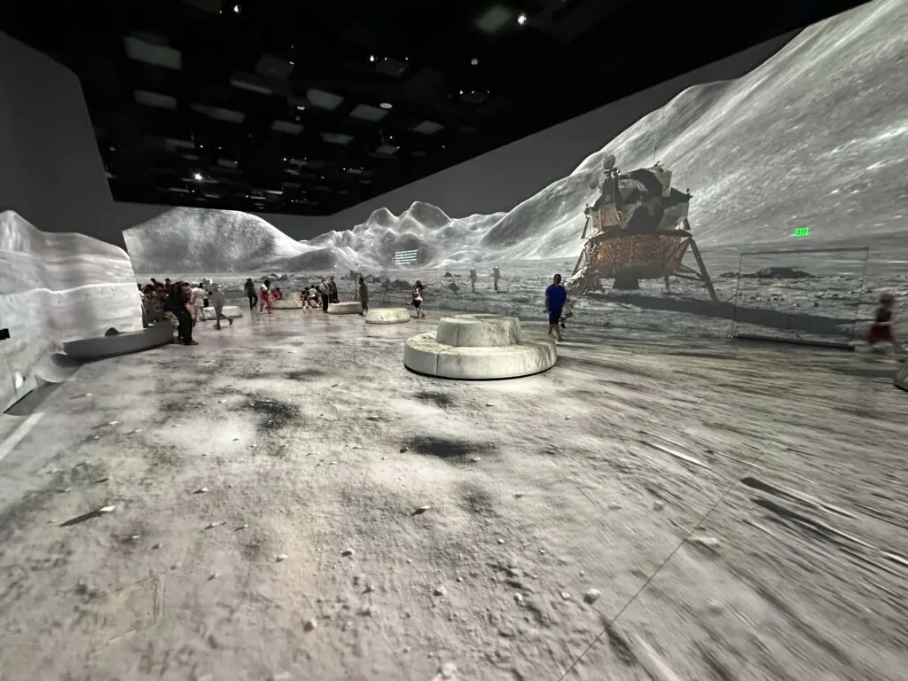 Surface of the moon, with a spacecraft in the background depicted in Illuminarium's theater. 