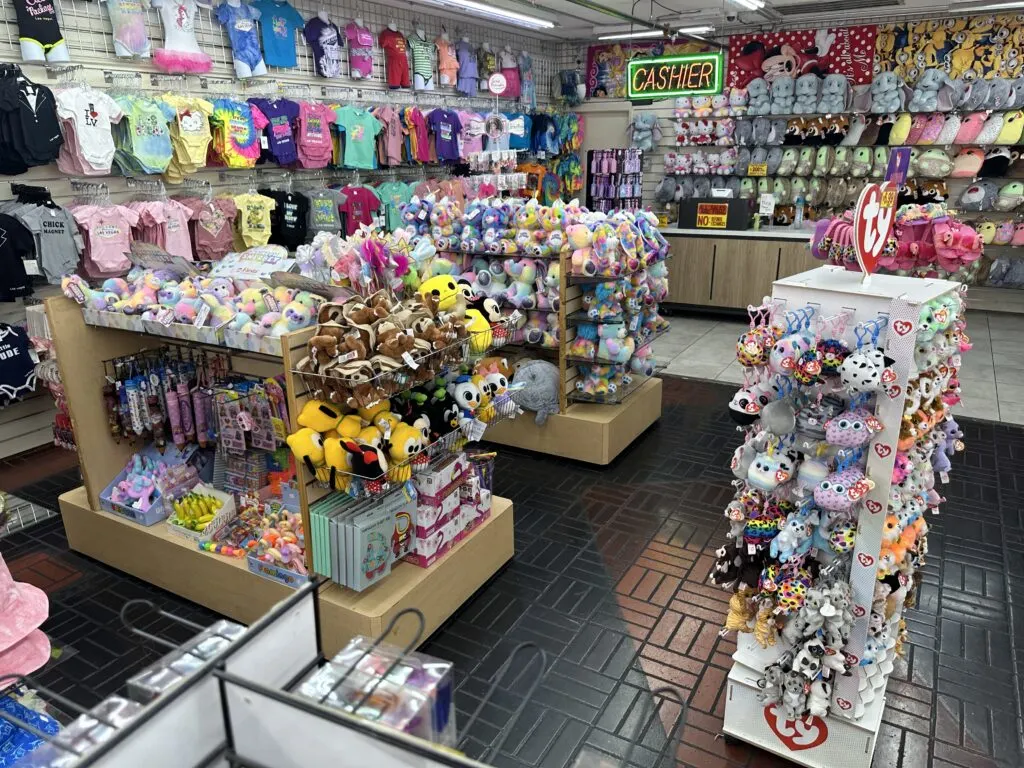 Toys and childrens clothing on display on racks and a backwall of a room in the shop. 