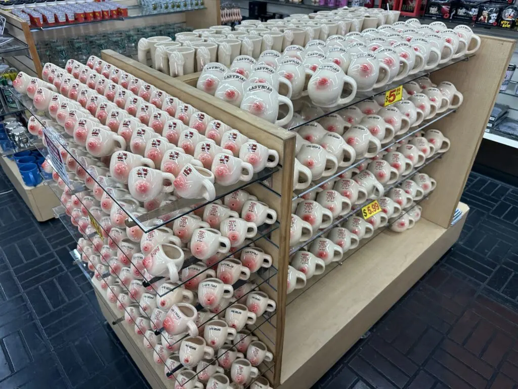 Mugs in the shape of human body parts are lined up like soldiers on a display rack. 