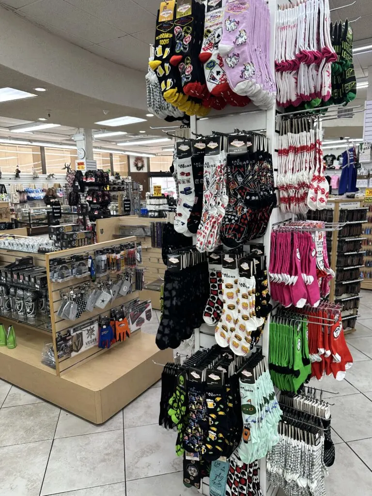 Socks with unique and fun designs hang from a pole in the store. 