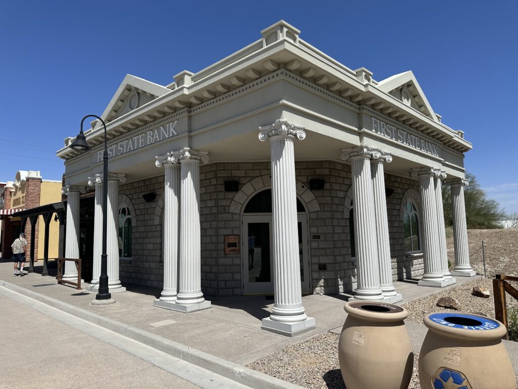Exterior of a bank at Boomtown 1905 with white stone walls and roman style pillars.