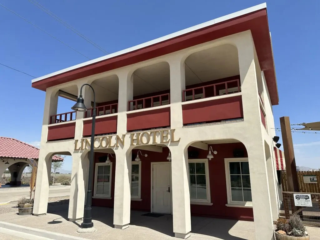 Exterior of the Lincoln Hotel, which has 2 stories and a balcony on the second level overlooking the street.