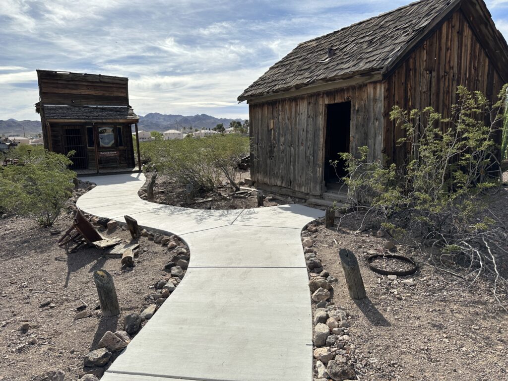 2 weathered structures along a path in the museum's ghost town. 
